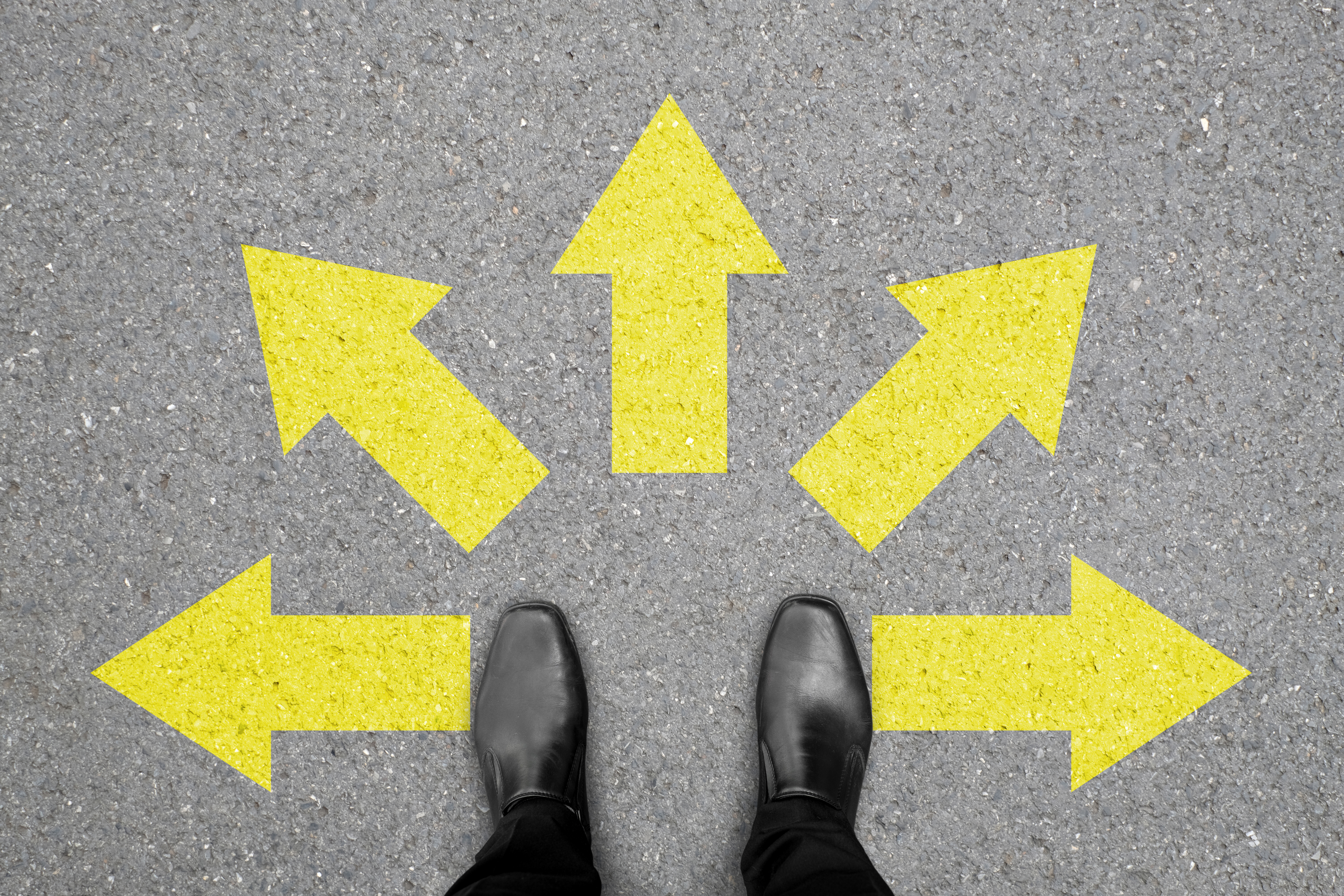 Person standing at a crossroads with five yellow arrows pointing in different directions
